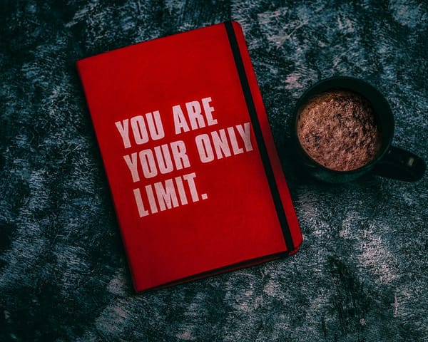A red journal with the words “You Are Your Only Limit” sits on a table.