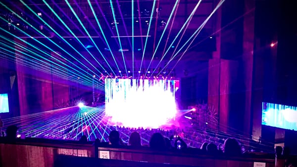 Concert with bright light and lazers emitting from the stage.